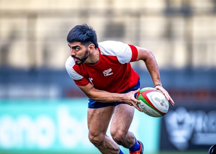 Intense rugby match with player running for a pass on the field.