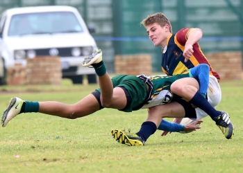 Two young athletes engaged in a dynamic rugby tackle during a competitive match.